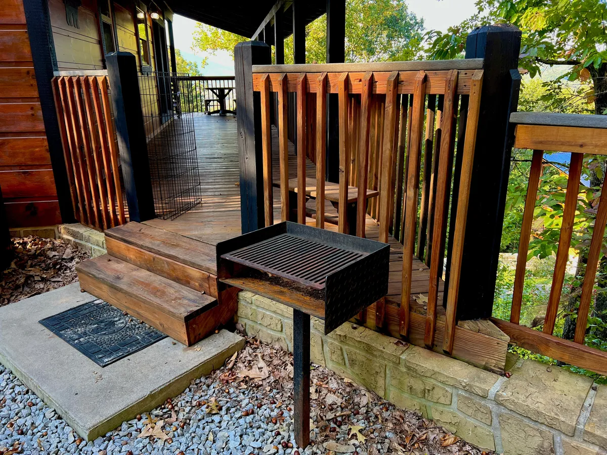 A view of the deck equipped with a charcoal grill, staircase, and sturdy railings, inviting guests to cook outdoors and enjoy al fresco meals. The scene suggests a lively atmosphere suitable for barbecues and casual hangouts, with space for movement and interaction.