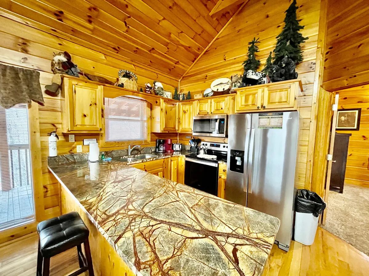 A close-up view of the kitchen features granite countertops, wooden cabinetry, stainless steel appliances, and decorative items, creating an inviting setting for cooking and hosting.